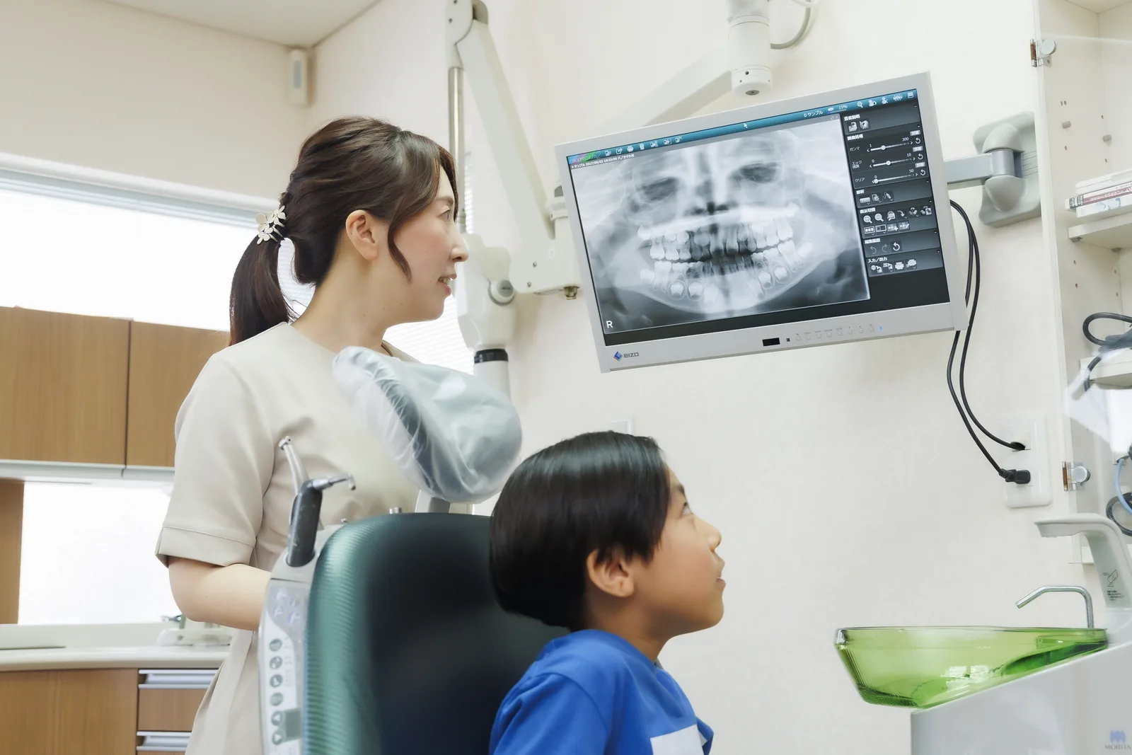 マウスピース型矯正装置とパノラマレントゲンを前に説明する歯科医師