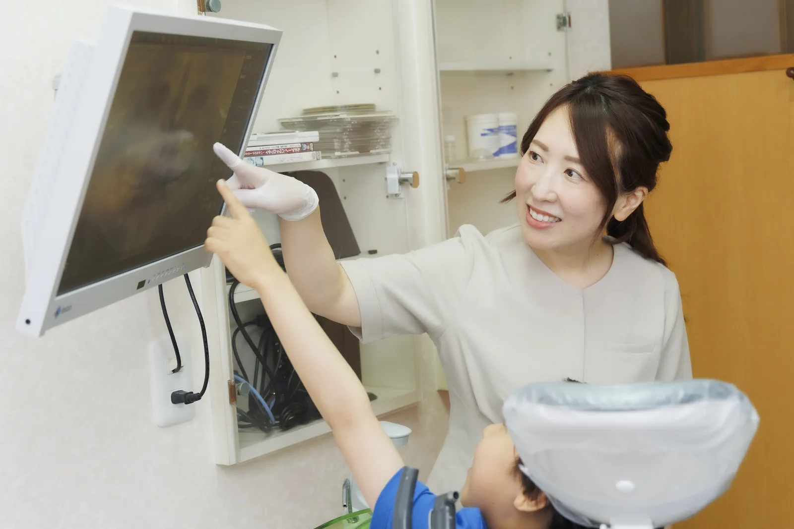 歯科衛生士がモニターの歯の画像を指して説明している様子