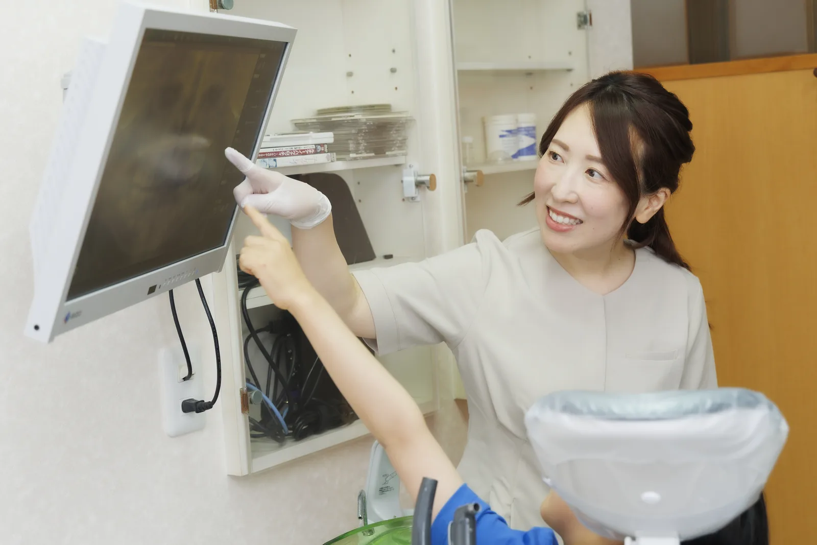 歯科衛生士がモニターの歯の画像を指して説明している様子